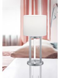 white table lamp stands on a bedside table in a hotel room. pink