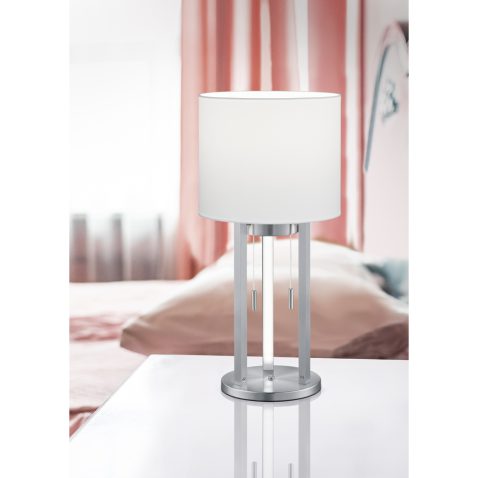 white table lamp stands on a bedside table in a hotel room. pink