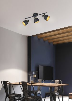 Modern sofa and dining table with iron chairs in the loft interior of a studio apartment. Dark concrete panel and wooden planks on the wall.